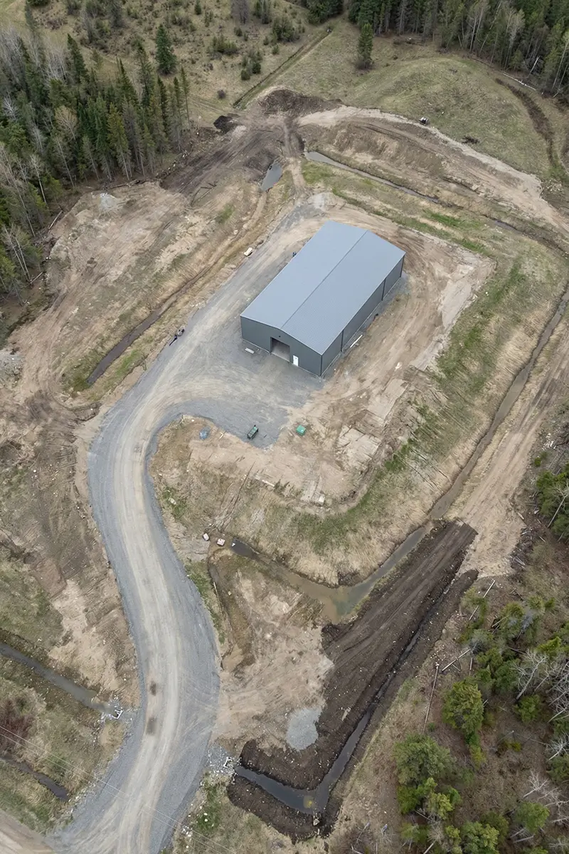 Aerial view of steel building site showing grading, drainage paths, and land preparation in Canada